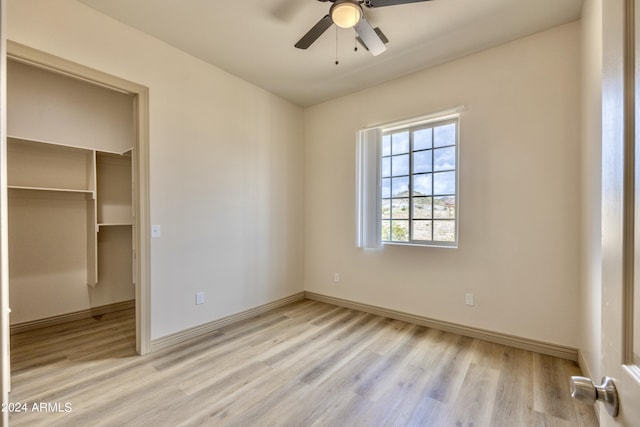 unfurnished bedroom featuring baseboards, a closet, wood finished floors, and a spacious closet