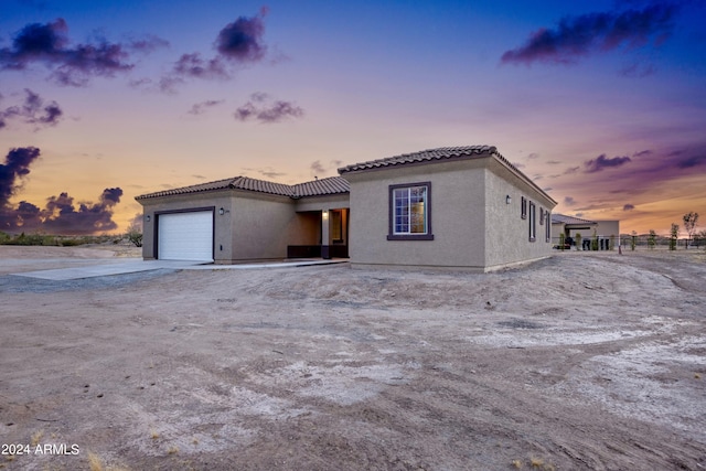 view of front of house featuring a garage, fence, stucco siding, driveway, and a tile roof