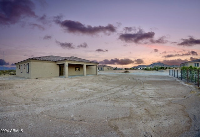 view of side of property featuring fence, a tile roof, and stucco siding