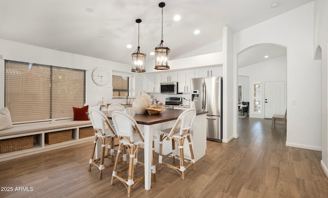 dining space with wood-type flooring and high vaulted ceiling