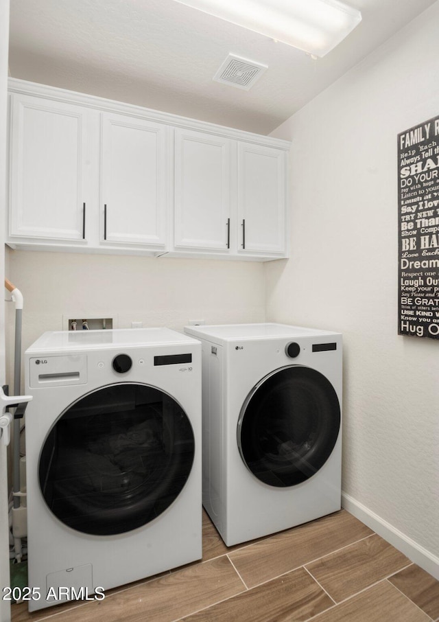 clothes washing area featuring cabinets, light hardwood / wood-style floors, and independent washer and dryer