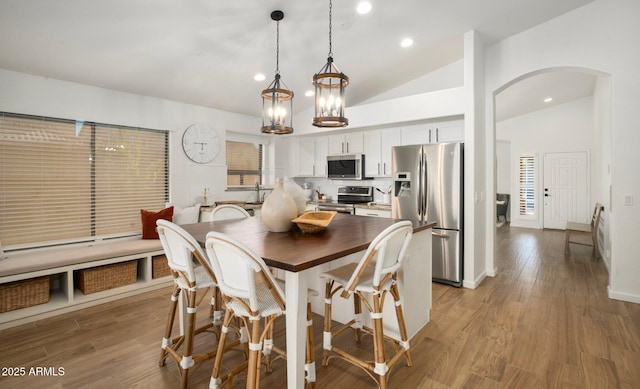 dining space with wood-type flooring and high vaulted ceiling