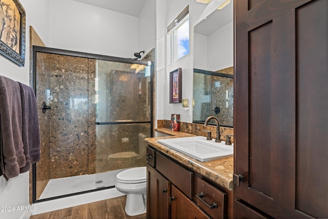 bathroom with hardwood / wood-style floors, vanity, toilet, and a shower with shower door