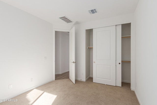 unfurnished bedroom with light colored carpet and a closet