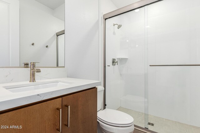 bathroom featuring vanity, toilet, and a shower with door