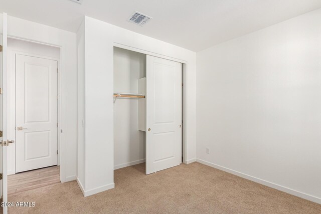 unfurnished bedroom featuring light colored carpet and a closet