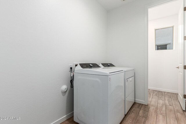 laundry room with washing machine and dryer and light wood-type flooring