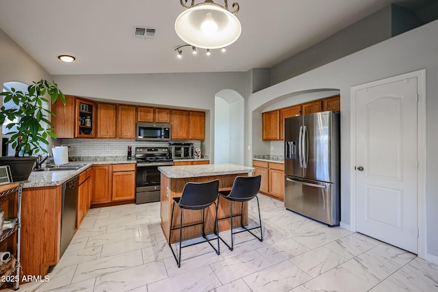 kitchen featuring vaulted ceiling, sink, backsplash, a center island, and stainless steel appliances