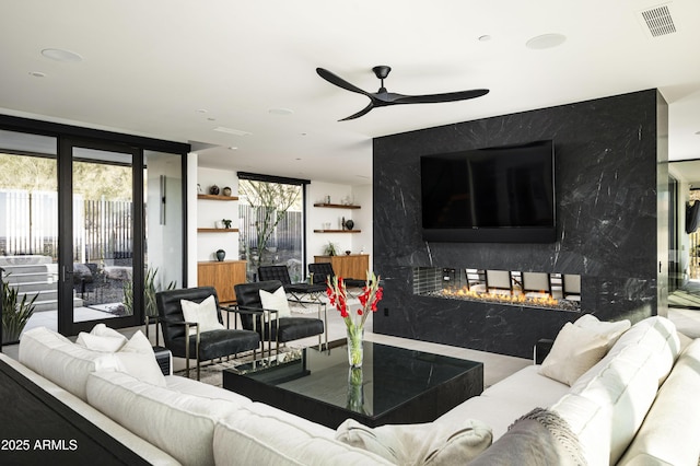 living room featuring ceiling fan, a high end fireplace, floor to ceiling windows, and a healthy amount of sunlight