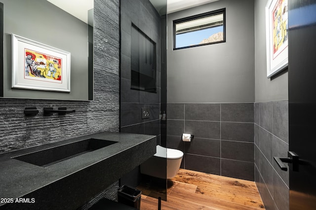 bathroom featuring sink, toilet, hardwood / wood-style floors, and tile walls