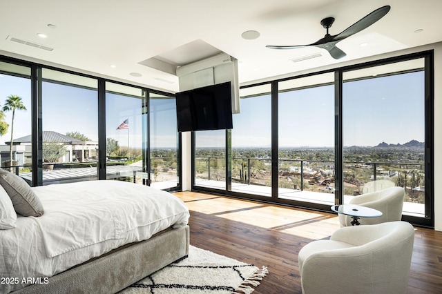 bedroom with expansive windows, hardwood / wood-style floors, and access to exterior