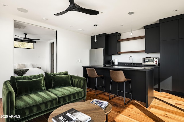 living room with sink, light hardwood / wood-style flooring, and ceiling fan