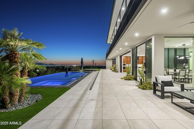 pool at dusk featuring a patio