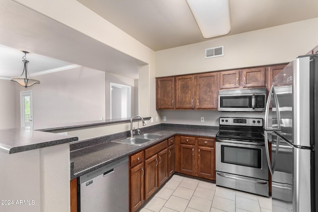 kitchen with sink, light tile patterned floors, ornamental molding, appliances with stainless steel finishes, and kitchen peninsula