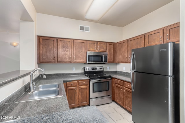 kitchen with light tile patterned floors, stainless steel appliances, and sink