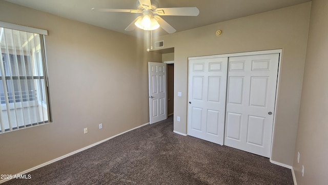 unfurnished bedroom with ceiling fan, a closet, and dark carpet