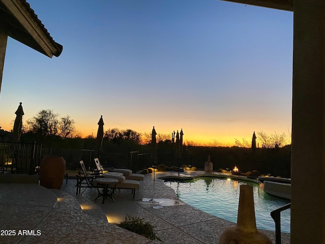 pool at dusk featuring a patio area