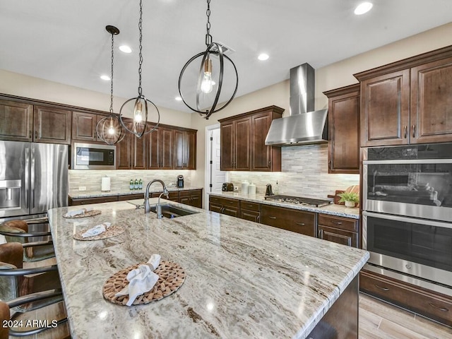 kitchen with a spacious island, stainless steel appliances, wall chimney range hood, and an inviting chandelier