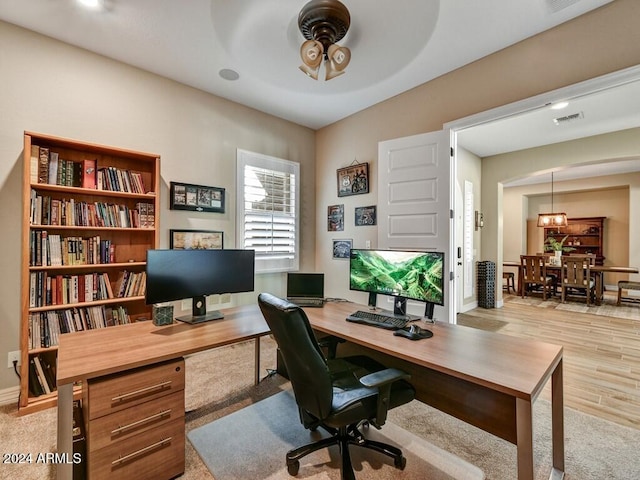 office with light wood-type flooring and ceiling fan