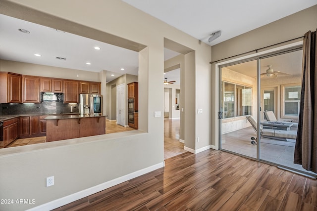 kitchen with black appliances, a breakfast bar, ceiling fan, and tasteful backsplash