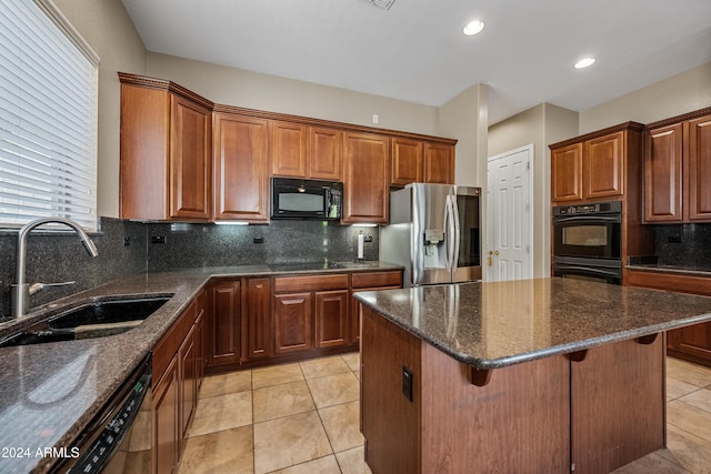 kitchen with dark stone countertops, sink, a center island, and black appliances