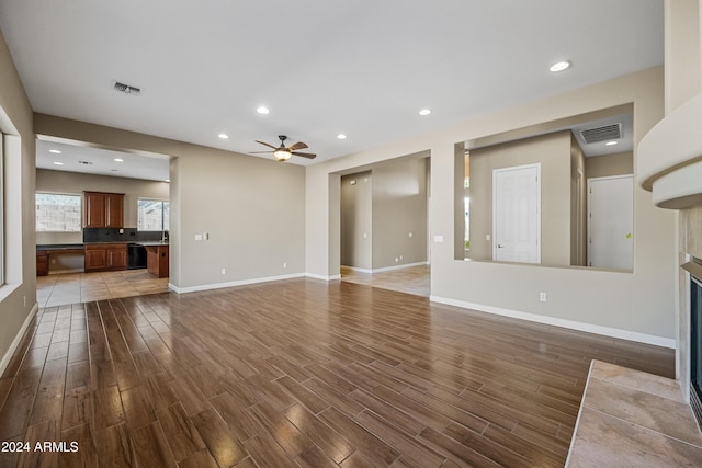 unfurnished living room featuring a tile fireplace and ceiling fan