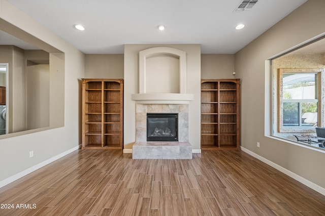 unfurnished living room featuring a tile fireplace, wood-type flooring, and washer / dryer