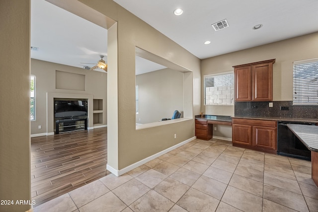 kitchen with ceiling fan, black dishwasher, backsplash, light tile patterned flooring, and built in desk