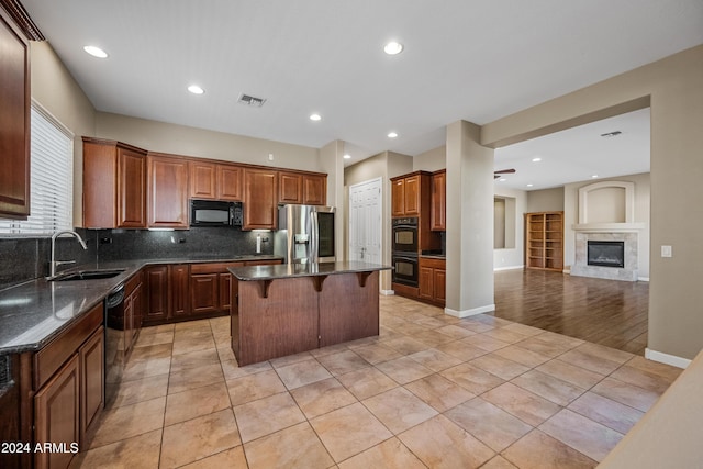 kitchen with light tile patterned flooring, sink, a center island, and black appliances