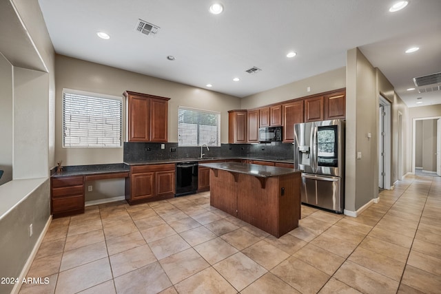 kitchen featuring a kitchen breakfast bar, sink, black appliances, light tile patterned floors, and a kitchen island