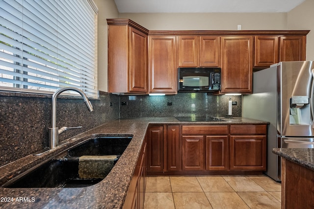 kitchen with backsplash, dark stone counters, black appliances, sink, and light tile patterned floors