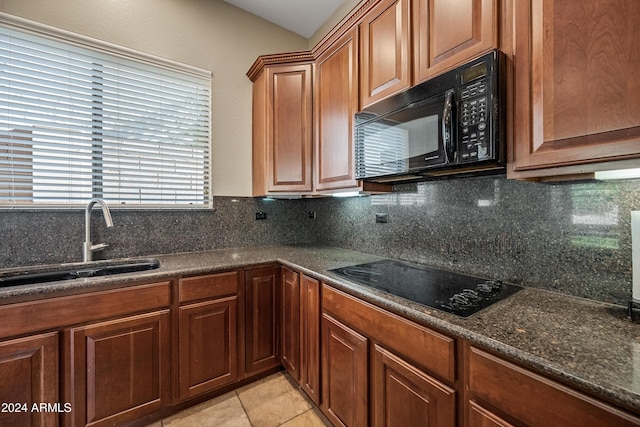 kitchen featuring tasteful backsplash, sink, light tile patterned flooring, and black appliances