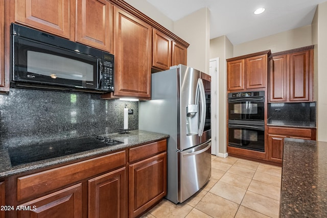 kitchen with light tile patterned floors, backsplash, dark stone counters, and black appliances