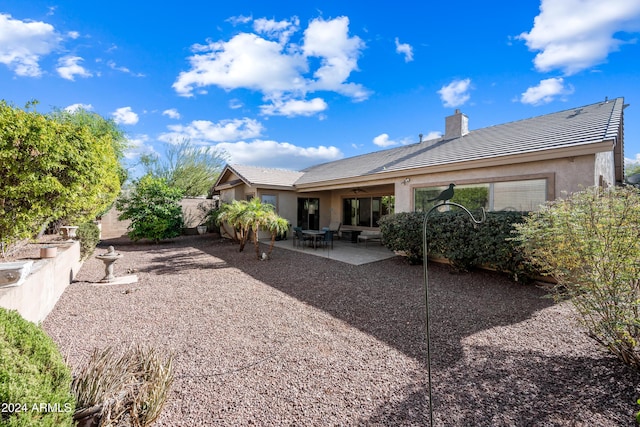 rear view of property with ceiling fan and a patio area