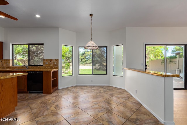 kitchen with dishwasher, backsplash, decorative light fixtures, and a healthy amount of sunlight