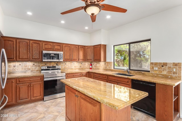 kitchen featuring light stone countertops, a sink, appliances with stainless steel finishes, a center island, and brown cabinetry