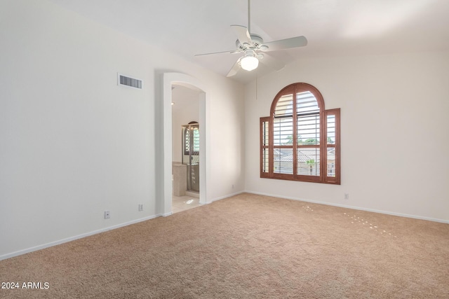 empty room featuring visible vents, arched walkways, a ceiling fan, light colored carpet, and lofted ceiling