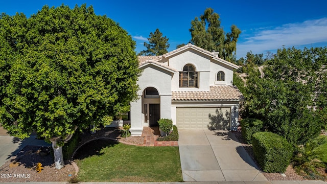 mediterranean / spanish house featuring a garage, concrete driveway, a tile roof, a front lawn, and stucco siding