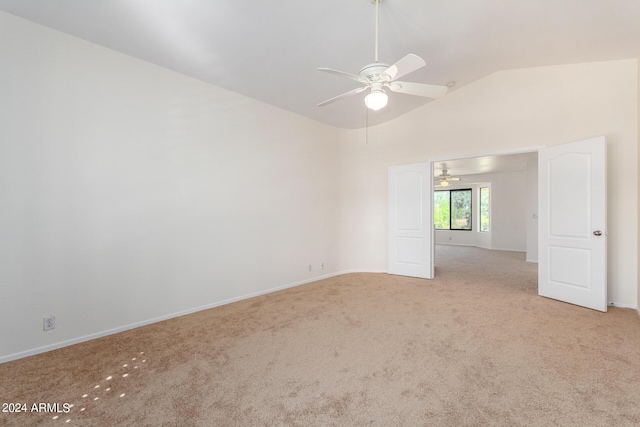 empty room with lofted ceiling, light carpet, a ceiling fan, and baseboards