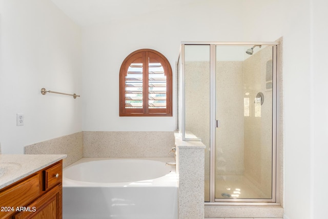 bathroom with a stall shower, a garden tub, and vanity