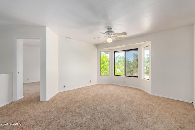 empty room with baseboards, visible vents, a ceiling fan, and light colored carpet