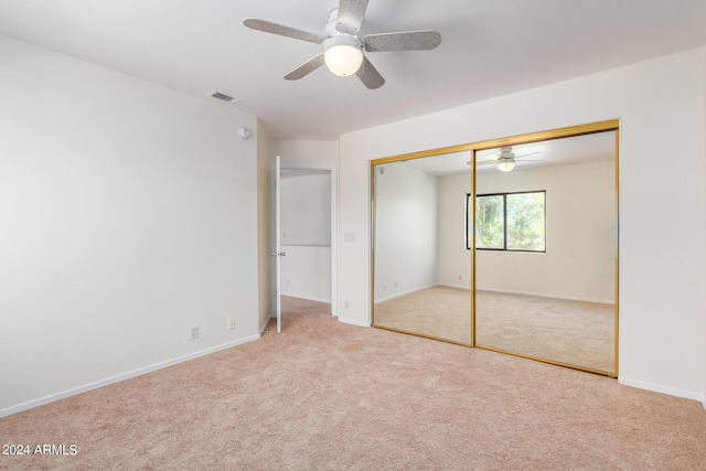 unfurnished bedroom featuring ceiling fan, light carpet, visible vents, baseboards, and a closet