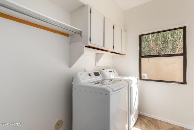 laundry room featuring washer and dryer, cabinet space, and baseboards