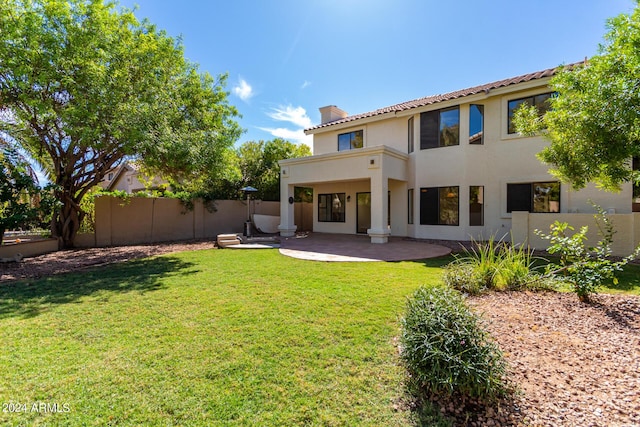 rear view of house featuring a lawn, a patio, a fenced backyard, a chimney, and stucco siding