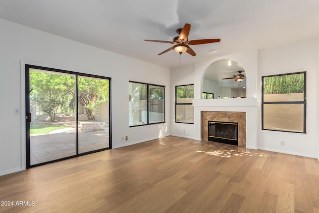 unfurnished living room featuring light wood-style floors, ceiling fan, a fireplace, and baseboards