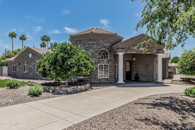 ranch-style home featuring a tiled roof, concrete driveway, and stone siding