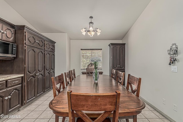 dining space featuring light tile patterned floors, baseboards, and a notable chandelier
