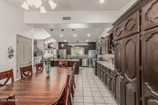 kitchen with dark brown cabinets, a center island, stainless steel appliances, tasteful backsplash, and visible vents