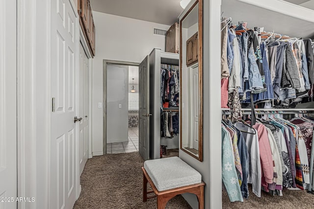 walk in closet with visible vents, carpet, and tile patterned floors
