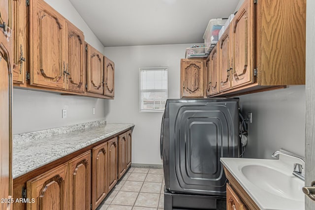 clothes washing area featuring a sink, light tile patterned floors, washer / clothes dryer, and cabinet space